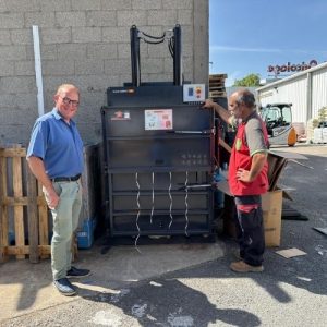 Un responsable de Mr.Bricolage Craponne et un technicien IDS Environnement posant devant le Clean Kompact 151 nouvellement installé sur le site, lors de la mise en service de la presse à balles.