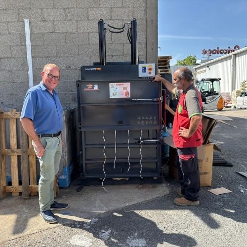 Un responsable de Mr.Bricolage Craponne et un technicien IDS Environnement posant devant le Clean Kompact 151 nouvellement installé sur le site, lors de la mise en service de la presse à balles.